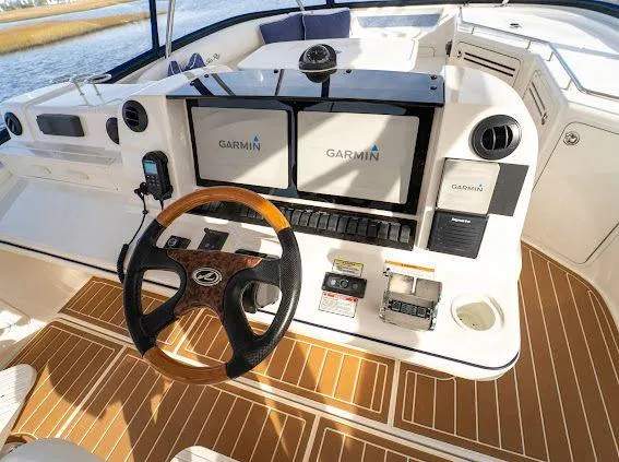 Slide: The Image of 2006 Sea Ray 580 Sedan Bridge helm with Garmin navigation displays and wood-accented steering wheel. - 26