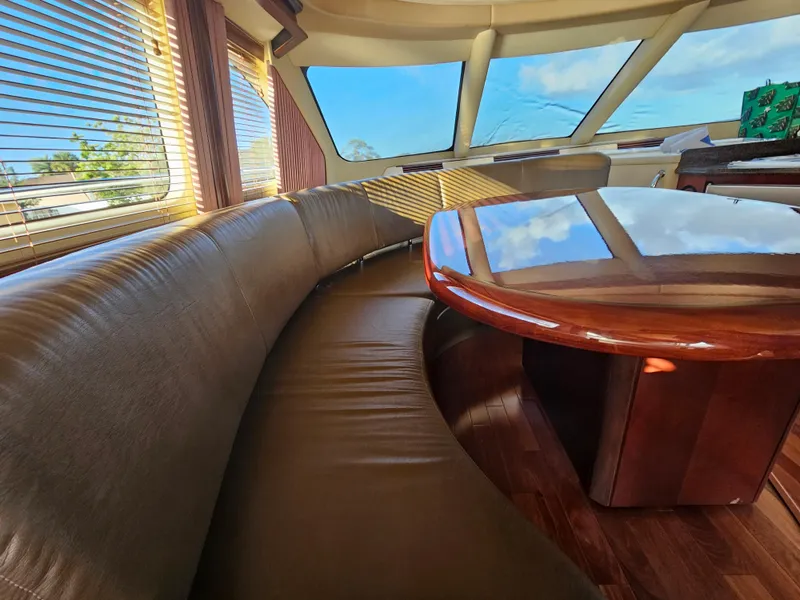 Slide: The Image of Luxurious interior of 2006 Sea Ray 580 Sedan Bridge with leather seating and wooden table. - 33
