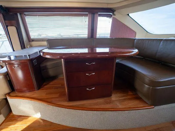 Slide: The Image of Luxurious interior of 2006 Sea Ray 580 Sedan Bridge with leather seating and wooden table. - 38