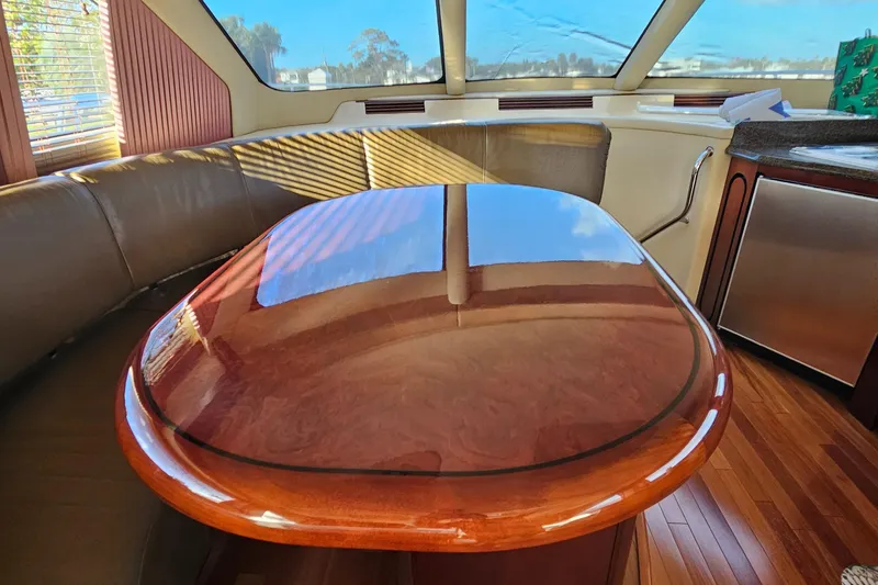 Slide: The Image of Interior of 2006 Sea Ray 580 Sedan Bridge with polished wooden table and leather seating. - 39