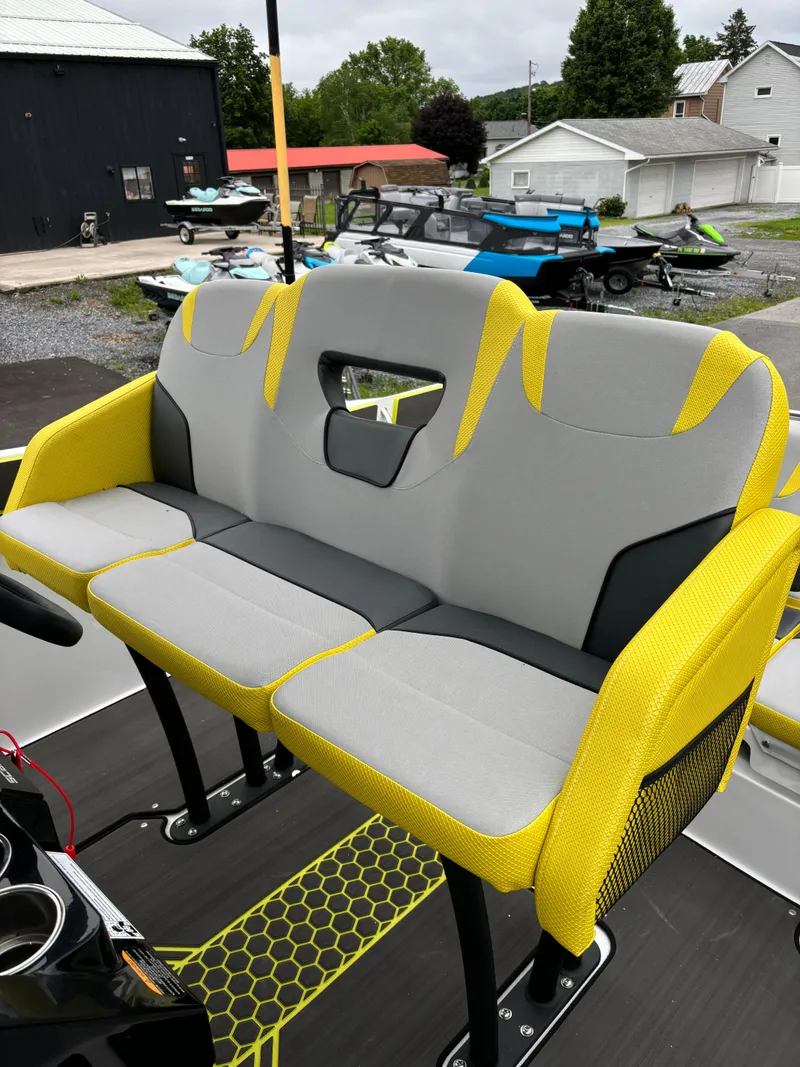 Slide: The Image of 2025 Scarab 255 Open SE boat seating with gray and yellow upholstery, outdoor setting. - 11