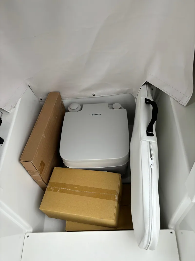 Slide: The Image of Storage compartment in 2025 Scarab 255 Open SE boat with portable toilet and boxes. - 8