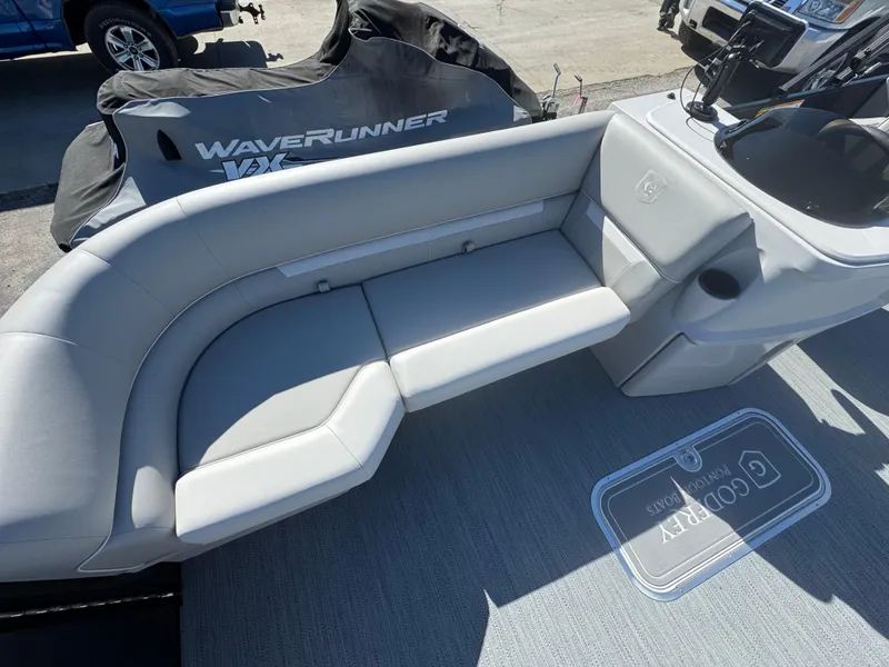 Slide: The Image of 2025 Godfrey EX2286SFLX pontoon boat with gray seating and WaveRunner in background. - 2