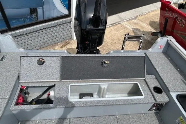 Slide: The Image of 2025 Lund 1675 Alaskan Tiller boat interior with storage compartments and motor. - 12