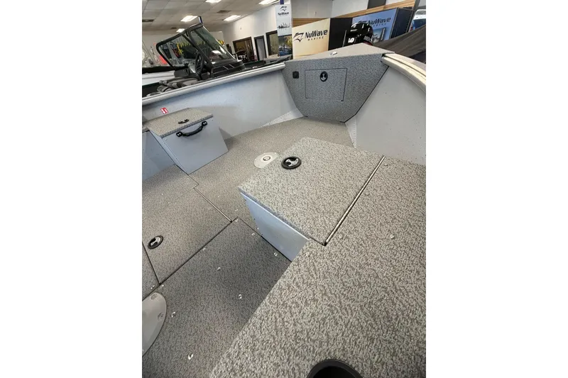 Slide: The Image of 2025 Lund 1675 Alaskan Tiller boat interior with gray carpeted flooring and storage compartments. - 21