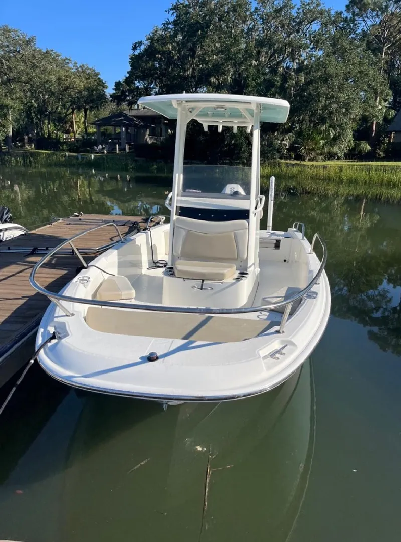 Slide: The Image of 2019 Boston Whaler 210 Dauntless boat docked on calm water. - 2