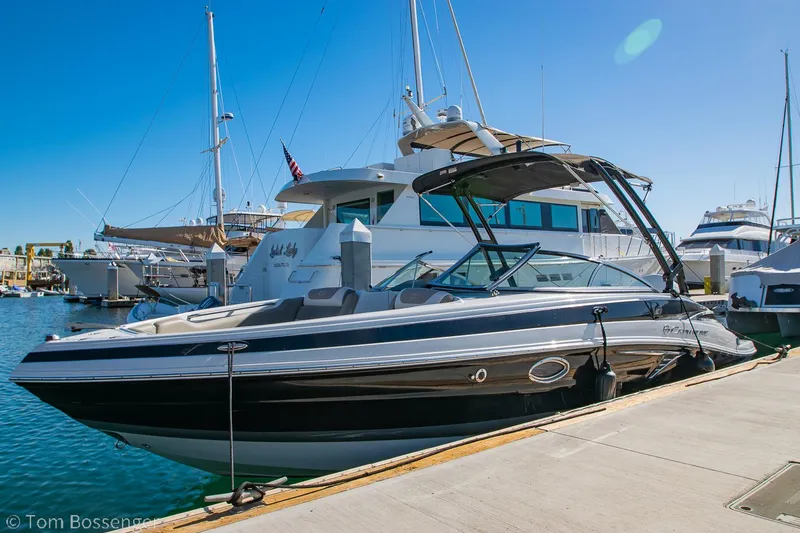 Slide: The Image of 2021 Crownline 255 XSS boat docked at marina under clear blue sky. - 0