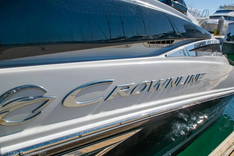 Slide: The Image of 2021 Crownline 255 XSS boat side view with logo in marina. - 1