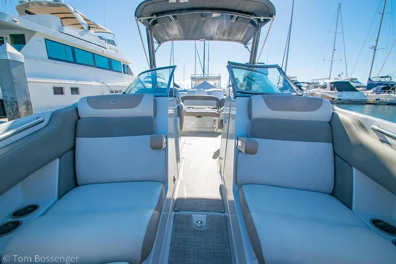 Slide: The Image of 2021 Crownline 255 XSS boat interior with plush seating at a marina. - 12