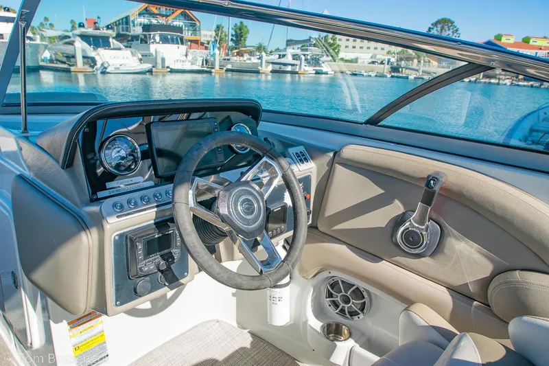 Slide: The Image of 2021 Crownline 255 XSS boat cockpit with steering wheel and dashboard, docked at marina. - 13