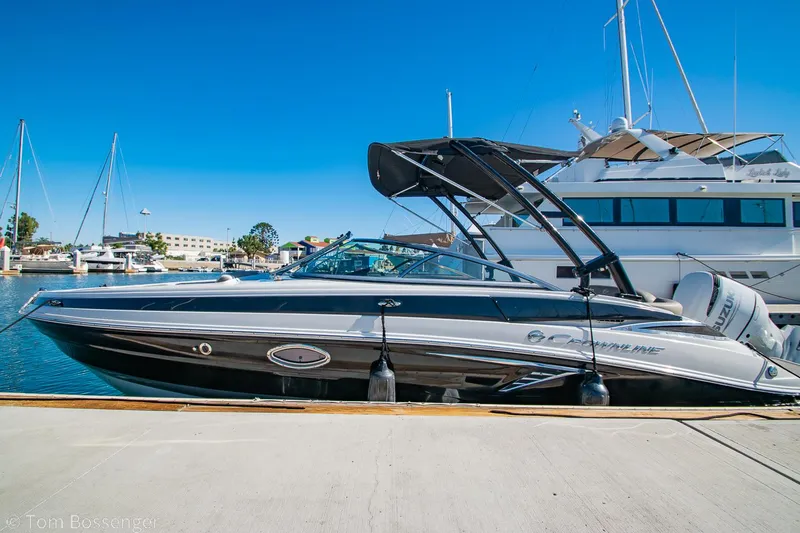Slide: The Image of 2021 Crownline 255 XSS boat docked at marina under clear blue sky. - 2