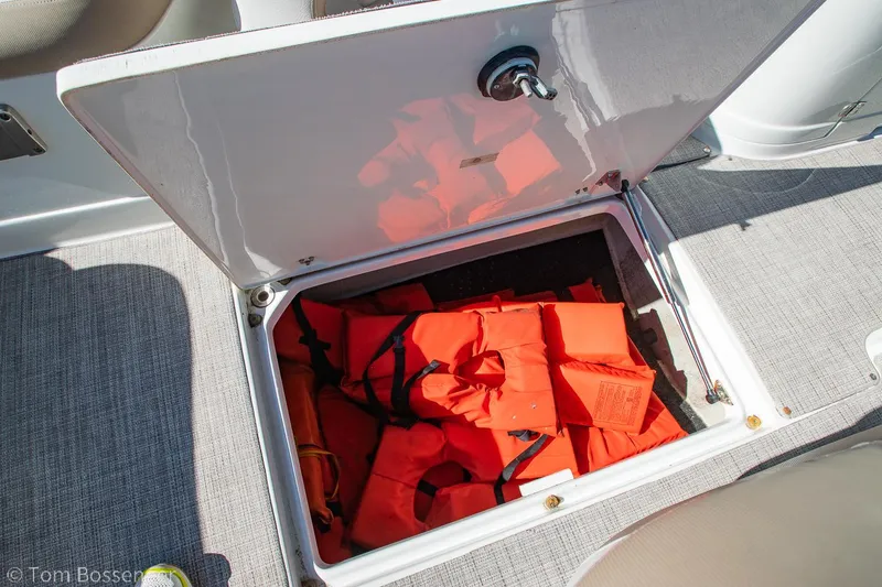 Slide: The Image of Open storage compartment on 2021 Crownline 255 XSS boat with orange life jackets. - 21