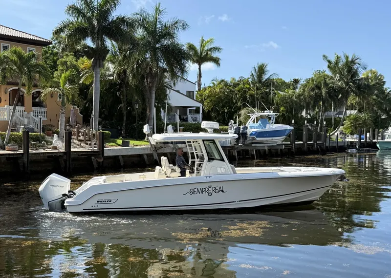 Slide: The Image of 2020 Boston Whaler 330 Outrage boat cruising near palm-lined waterfront homes. - 1
