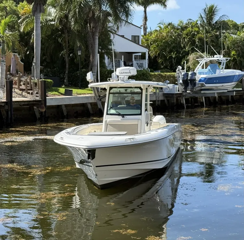 Slide: The Image of 2020 Boston Whaler 330 Outrage boat cruising on a calm waterway, surrounded by lush greenery. - 10