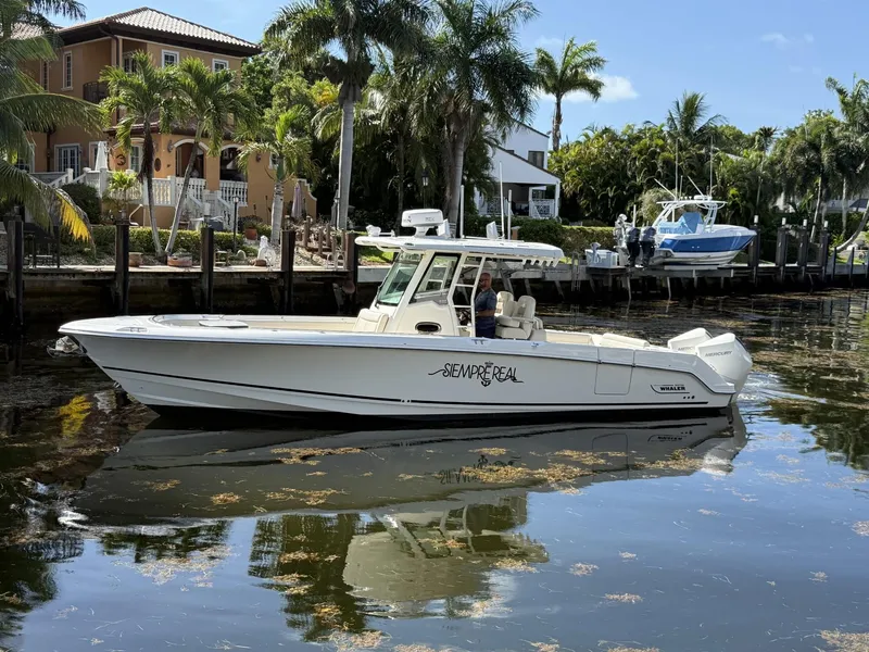 Slide: The Image of 2020 Boston Whaler 330 Outrage boat docked near waterfront homes, surrounded by palm trees. - 11