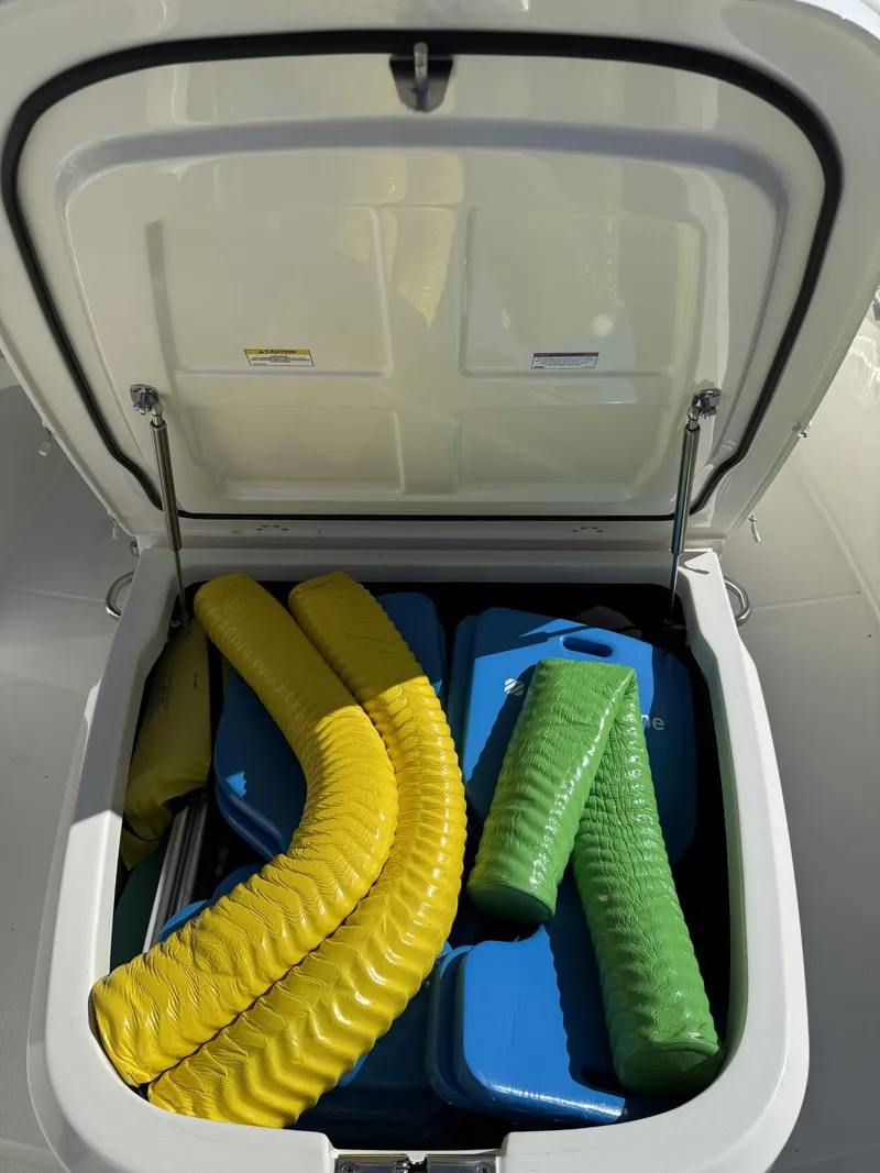 Slide: The Image of Open storage compartment on 2020 Boston Whaler 330 Outrage, filled with colorful flotation devices. - 20