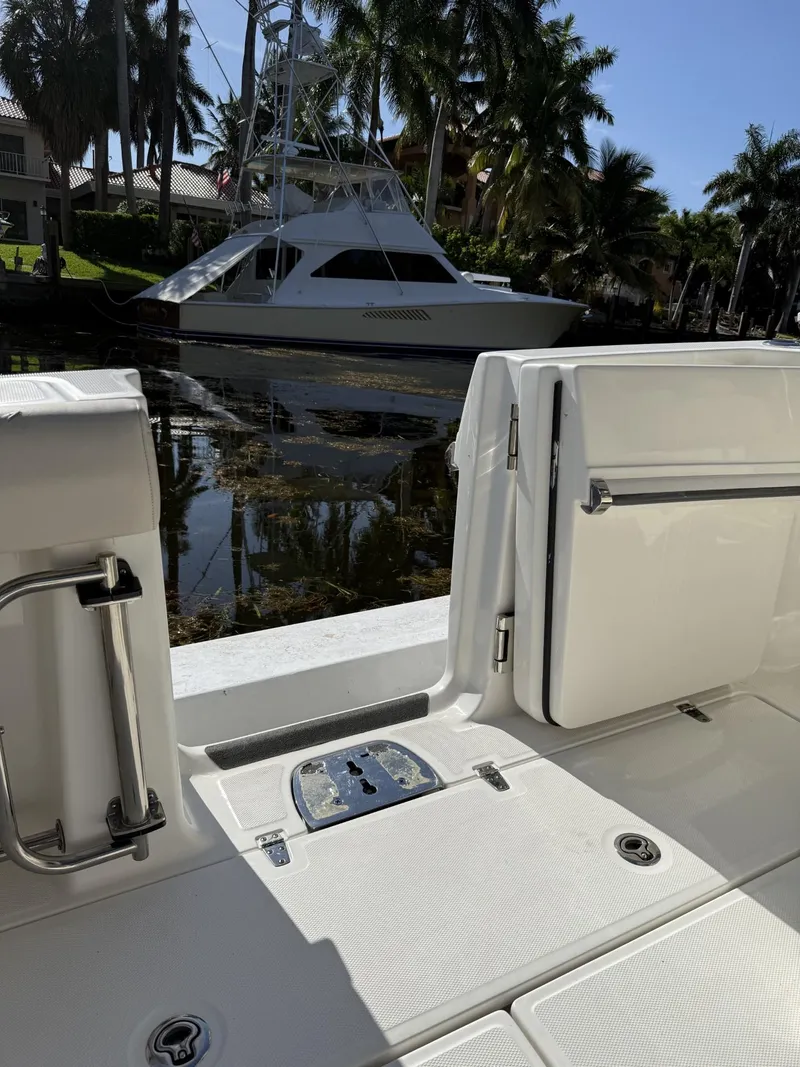 Slide: The Image of 2020 Boston Whaler 330 Outrage boat interior with docked yacht and palm trees in background. - 21