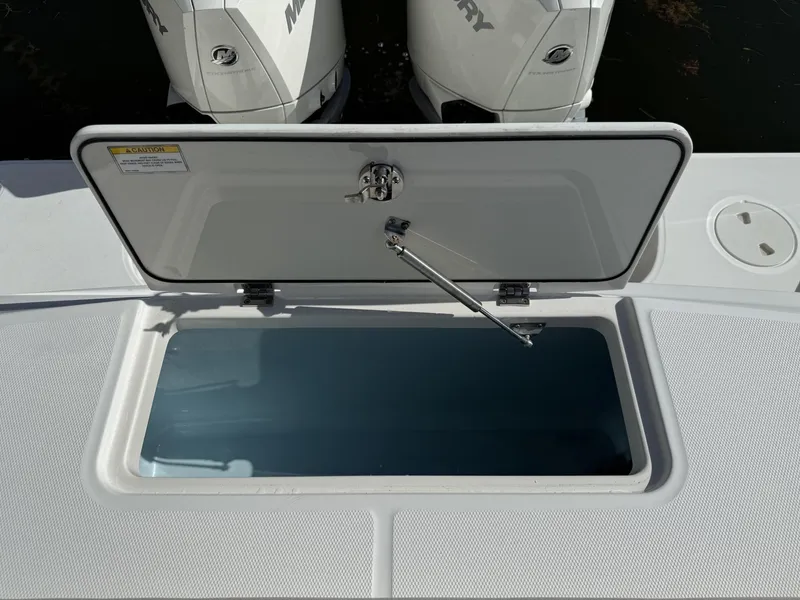 Slide: The Image of Open storage compartment on a 2020 Boston Whaler 330 Outrage boat, with Mercury engines visible. - 26