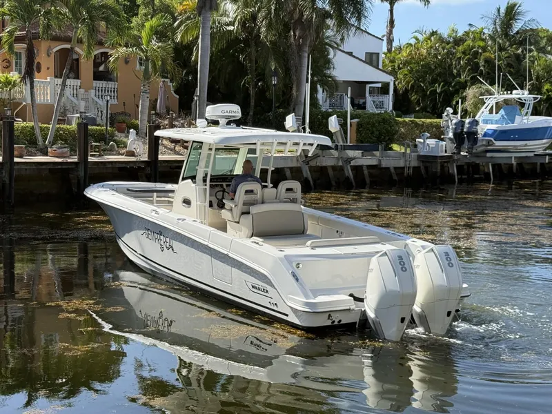 Slide: The Image of 2020 Boston Whaler 330 Outrage boat cruising near a waterfront property with palm trees. - 7