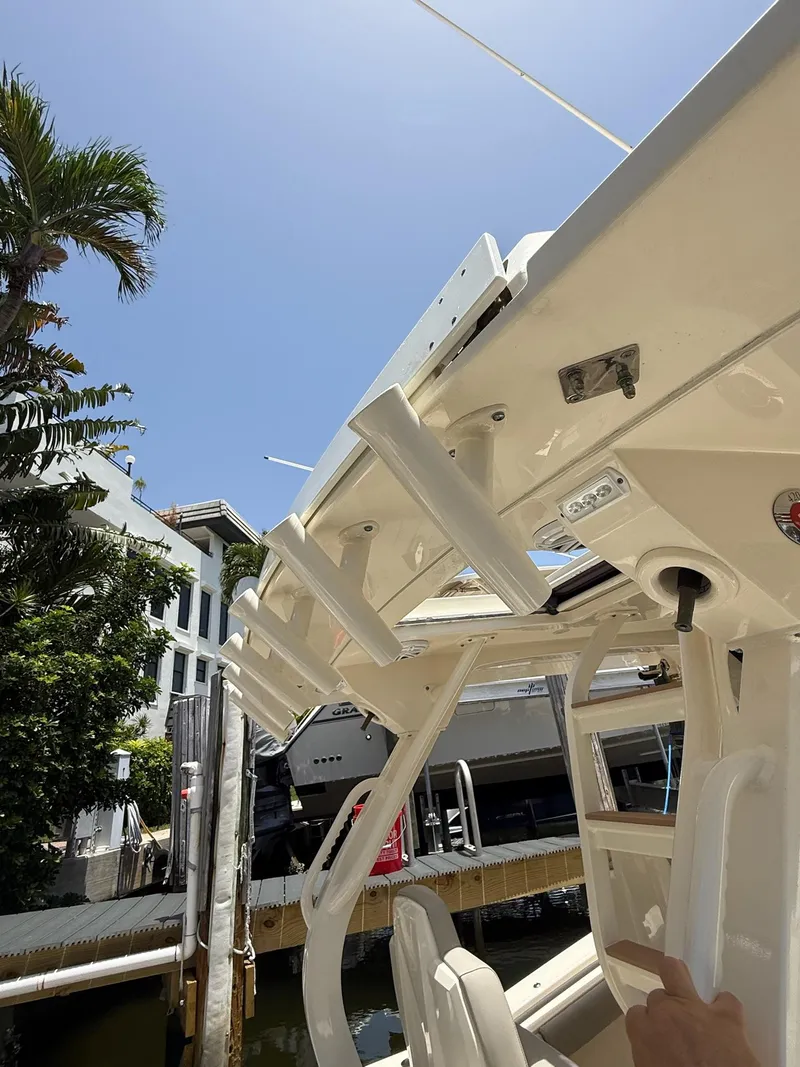 Slide: The Image of 2019 Scout 420 LXF boat docked, surrounded by palm trees and other boats. - 17