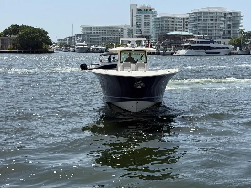 Slide: The Image of 2019 Scout 420 LXF boat cruising in a marina with modern buildings in the background. - 3