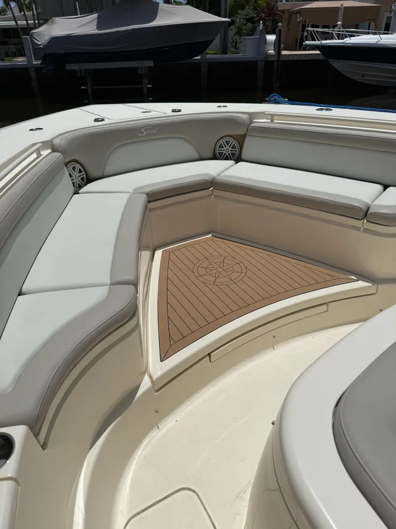 Slide: The Image of 2019 Scout 420 LXF boat interior with seating and table, docked near waterfront homes. - 39