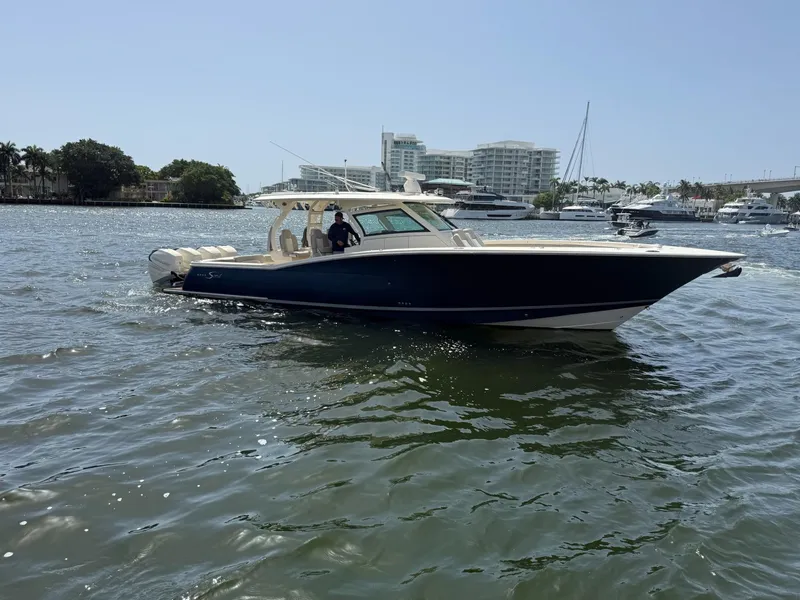 Slide: The Image of 2019 Scout 420 LXF boat cruising on a sunny day in a marina. - 4
