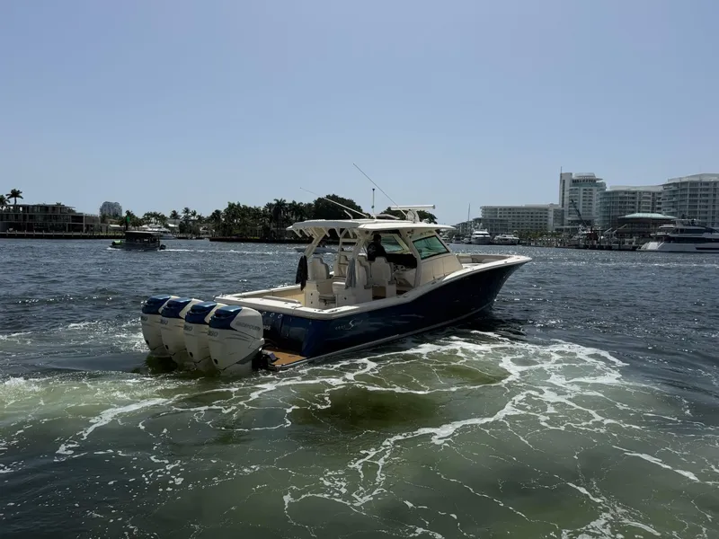 Slide: The Image of 2019 Scout 420 LXF boat cruising on a sunny day near waterfront buildings. - 6