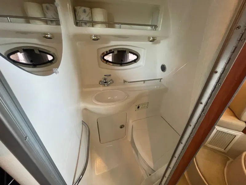 Slide: The Image of 2004 Chaparral Signature 290 bathroom with sink, toilet, and porthole windows. - 18