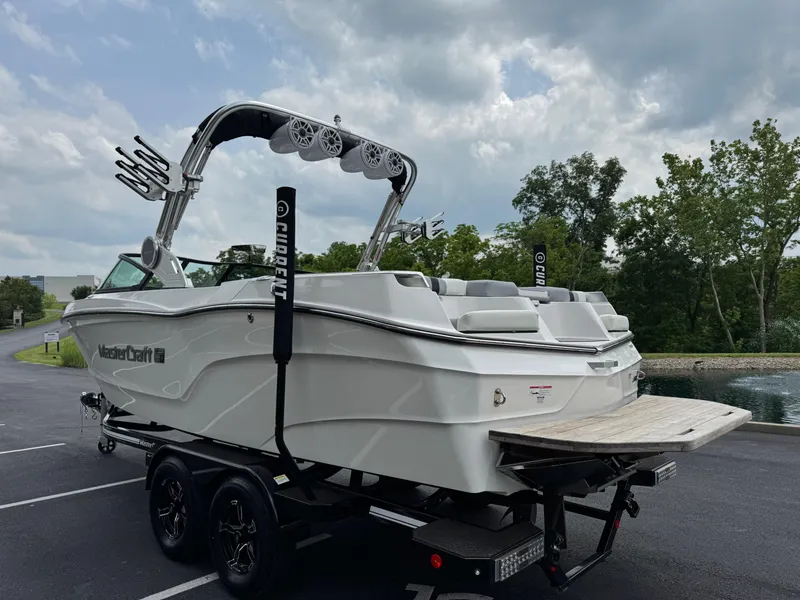Slide: The Image of 2023 MasterCraft XT23 boat on trailer, parked near a pond under cloudy skies. - 5