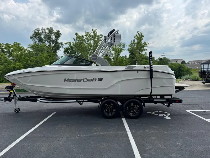 Slide: The Image of 2023 MasterCraft XT23 boat on trailer in parking lot, cloudy sky background. - 6