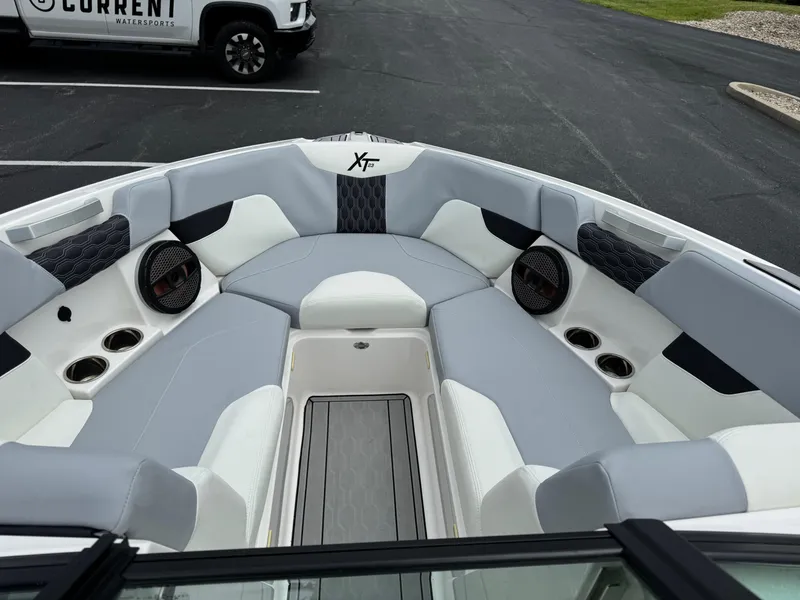 Slide: The Image of 2023 MasterCraft XT23 boat interior with gray and white seating, cup holders, and speakers. - 8