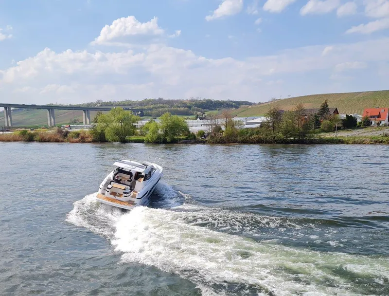 Slide: The Image of 2023 Bavaria SR41 COUPE cruising on a scenic river with a bridge and countryside backdrop. - 4