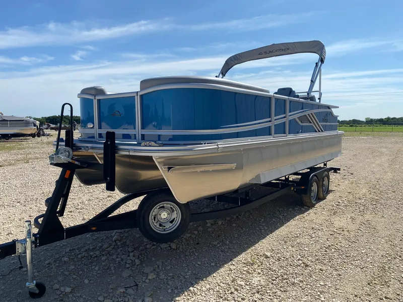 Slide: The Image of 2025 SunCatcher Fusion 324SL pontoon boat on trailer, parked on gravel lot. - 4