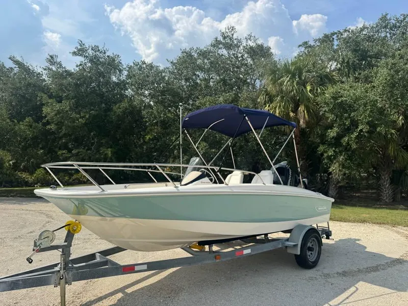 Slide: The Image of 2016 Boston Whaler 170 Super Sport boat on trailer, parked outdoors with trees in background. - 10