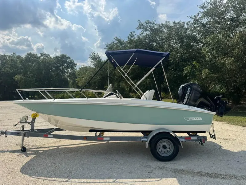 Slide: The Image of 2016 Boston Whaler 170 Super Sport boat on trailer, parked outdoors under cloudy sky. - 12