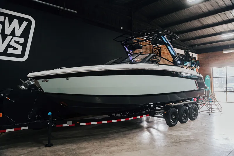 The Image of 2025 Cobalt R8 Surf boat on trailer in showroom setting. - 0