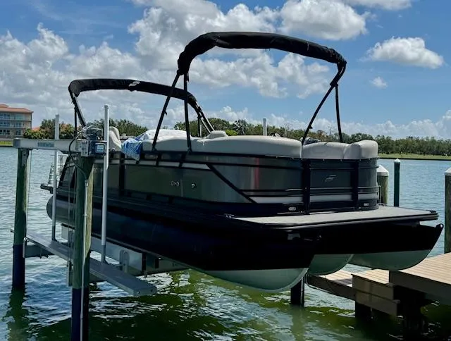 Slide: The Image of 2022 Starcraft CX 25 Q DH pontoon boat on lift, under a partly cloudy sky. - 4