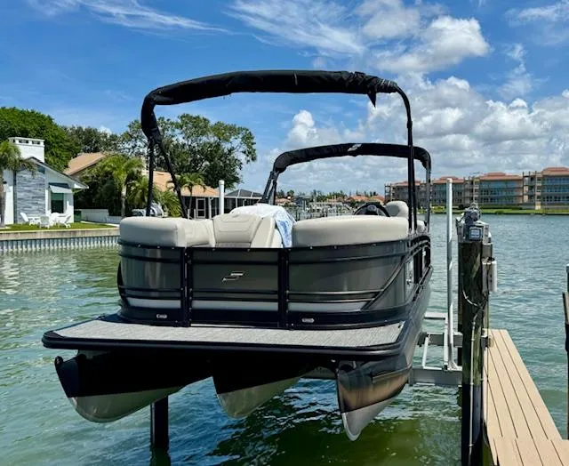 Slide: The Image of 2022 Starcraft CX 25 Q DH pontoon boat docked on a lift by waterfront homes. - 6