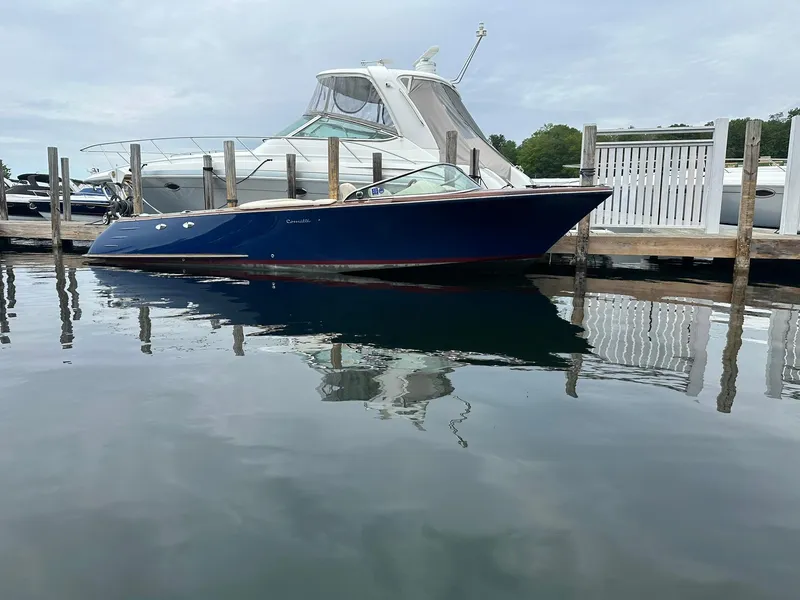 Slide: The Image of 2015 Comitti Venezia 22 boat docked on calm water, reflecting its sleek design. - 1