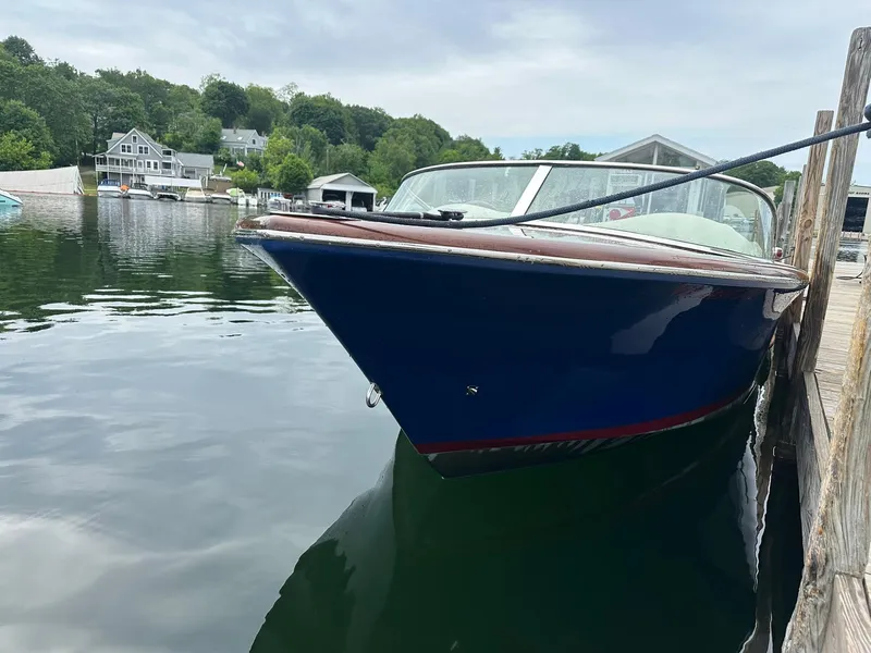 Slide: The Image of 2015 Comitti Venezia 22 boat docked on calm water, surrounded by lush greenery. - 4