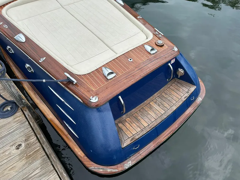 Slide: The Image of 2015 Comitti Venezia 22 boat with wooden deck and blue hull, docked by the water. - 8