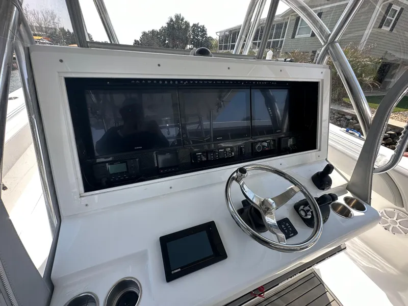 Slide: The Image of Control panel of 2021 SeaHunter 46 CTS boat with steering wheel and navigation screens. - 2