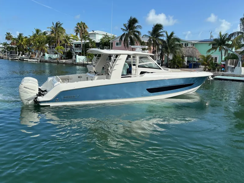 Slide: The Image of 2017 Boston Whaler 420 Outrage boat on clear water near palm trees and houses. - 10