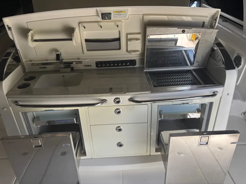 Slide: The Image of 2017 Boston Whaler 420 Outrage boat kitchen with grill, sink, and storage compartments. - 29