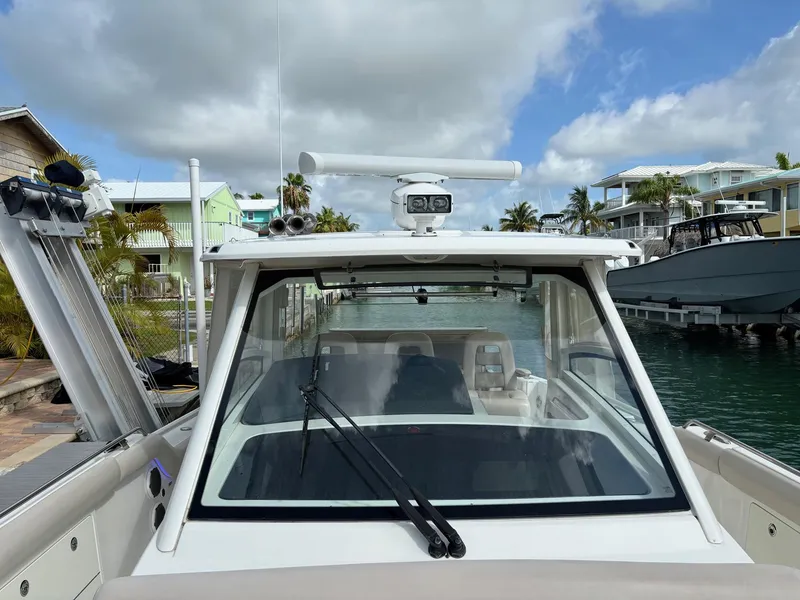 Slide: The Image of 2017 Boston Whaler 420 Outrage boat docked, showcasing helm and windshield under cloudy sky. - 41