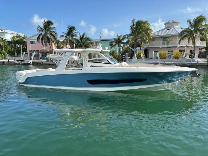 Slide: The Image of 2017 Boston Whaler 420 Outrage boat docked near tropical waterfront homes. - 9
