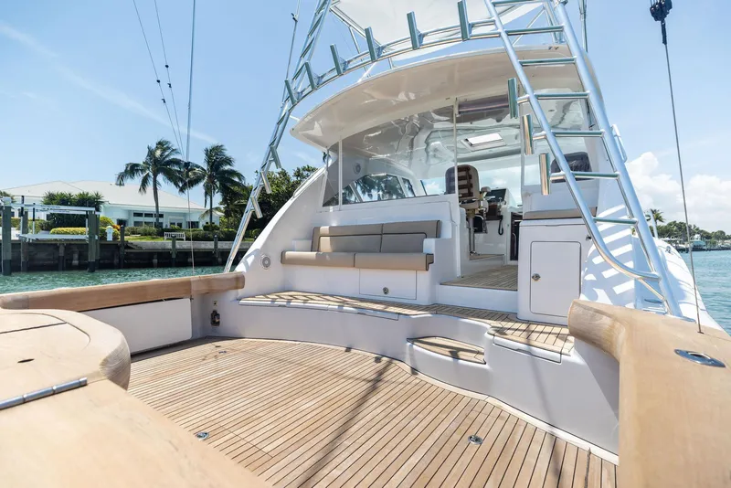 Slide: The Image of 2016 Hatteras Express Sportfish yacht with spacious deck and seating, docked near palm trees. - 25