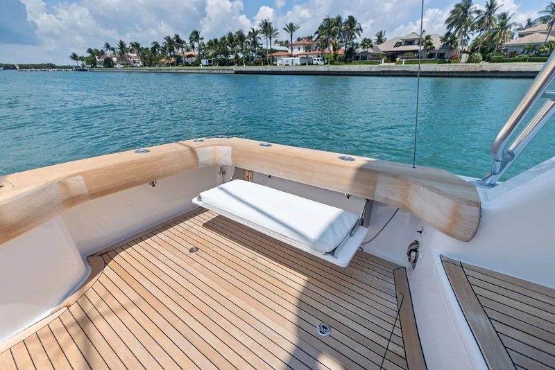 Slide: The Image of 2016 Hatteras Express Sportfish boat deck with wooden finish and scenic waterfront view. - 30