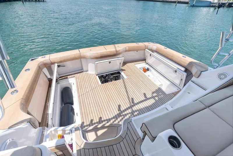 Slide: The Image of 2016 Hatteras Express Sportfish boat deck with open storage compartments, docked on calm water. - 33